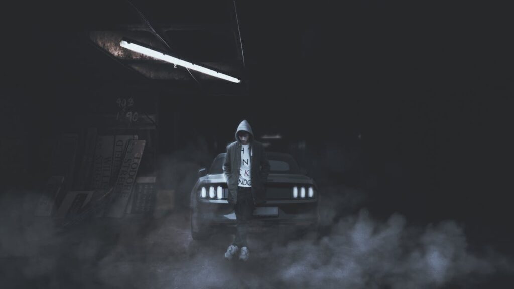 Grayscale Photography of Man Leaning Beside Car