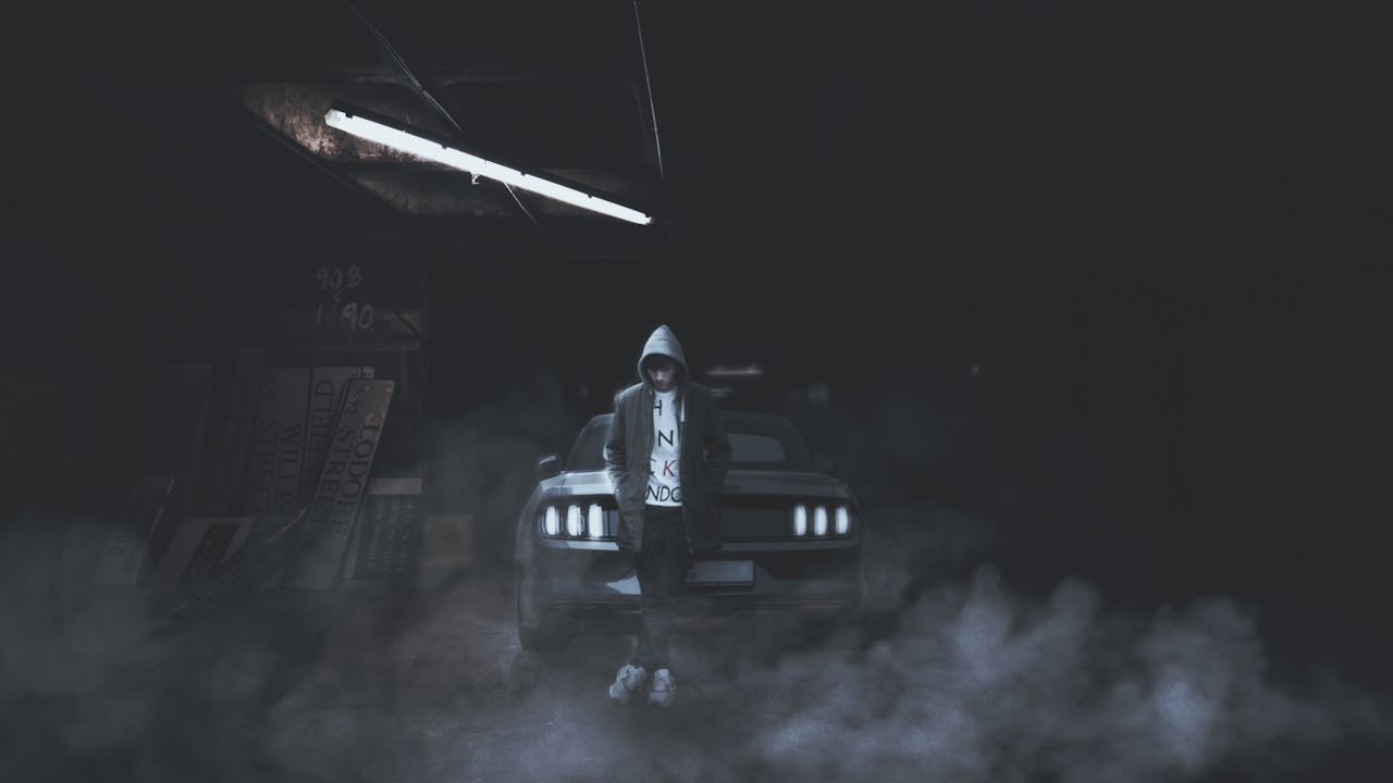 Grayscale Photography of Man Leaning Beside Car